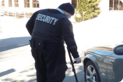 Un gardien de sécurité Harris en patrouille à pied près de voitures stationnées
